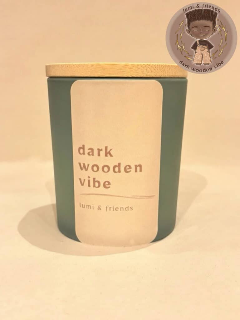 duftlys, matgrønt glas med bambuslåg og pastel brun label. tekst med dark wooden vibe, duftlys med duft af sandalwood, kanelte og ristet kastanje. billede i højre top hjørne af karakter til lyset, wenge wood, mørk, dyb og træ eventyrlig tegnet figur.